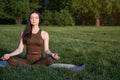 Close-up of a woman& x27;s hands on a background of green grass and a gymnastic mat. Young woman practices yoga in the