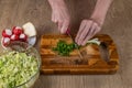 Close-up of woman& x27;s hands chopping green onions with a kitchen knife for making salad on a wooden cutting board Royalty Free Stock Photo