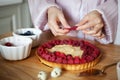 Close up of woman's hands decorating raspberry tart, cooks delicious pie with fresh berries and cream cheese Royalty Free Stock Photo