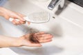 Close-up of woman& x27;s hands holding comb over sink and shows big clump of lost hair lies on palm. Concept of baldness Royalty Free Stock Photo