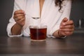 Close-up woman's hands holding a teaspoon with white sugar above a glass cup of freshly made black tea in the home Royalty Free Stock Photo