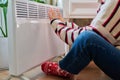 Close-up of woman hands legs warming near electric heating radiator Royalty Free Stock Photo