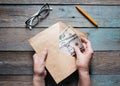 Close up of woman& x27;s hands puts American dollar bills in an envelope on wooden desktop Royalty Free Stock Photo