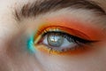 Close-up of a womans eye with vibrant orange and blue eyeshadow, creating a bold and striking look, A bold and colorful eyeshadow
