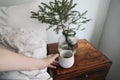 Close-up of womans hand holding cup of hot coffee, black tea drink. Morning breakfast in bedroom. Night table with Royalty Free Stock Photo