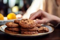 Close up Womans hand reaches for chocolate cookies, balancing them with orange juice