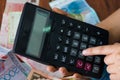 Close up womans hands holding calculator, money bills lying in background Royalty Free Stock Photo