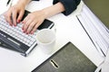 Close up of womans hands typing on laptop with folders and mug Royalty Free Stock Photo