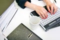 Close up of womans hands typing on laptop with folders and mug Royalty Free Stock Photo