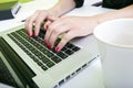 Close up of womans hands typing on laptop with mug in foreground Royalty Free Stock Photo