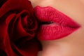 Close-up of womans lips with fashion red glossy makeup. Lips with lipstick closeup. Beautiful woman lips with rose.