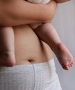 close up of woman belly and baby feet, mother holding baby