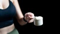 Close up of women hand holding measuring scoop of whey protein preparing protein shake