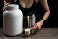 Close up of women with measuring scoop of whey protein, jar and shaker bottle, preparing protein shake