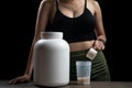 Close up of women with measuring scoop of whey protein, jar and shaker bottle, preparing protein shake