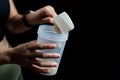 Close up of women with measuring scoop of whey protein and shaker bottle, preparing protein shake