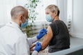 woman in a protective mask is vaccinated in a medical office.