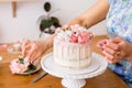 Close-up of women`s hands decorating the cake with fresh flowers Royalty Free Stock Photo