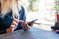 Close up of women`s hands holding cell telephone ander a table in a cafe. Girl watching video on mobile phone or use social Royalty Free Stock Photo