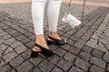 Close-up of women`s legs in black summer sandals in jeans with a leather bag on street Royalty Free Stock Photo