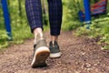 Close-up of women`s legs in green sneakers and pants in a cage go on a forest road. HLS, walk in the open air Royalty Free Stock Photo