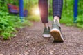 Close-up of women`s legs in green sneakers and pants in a cage go on a forest road. HLS, walk in the open air Royalty Free Stock Photo