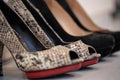 A close up of a women's shoe, snake leather peep toe and black suede pumps