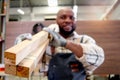 Close-up of wood planks that be carried by middle-aged African carpenter wears apron, worker man makes wooden furniture in Royalty Free Stock Photo