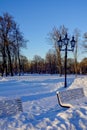 Close up of a wooden benches covered with a lot of white snow. Old style street lantern. Park Kadriorg, trees on the Royalty Free Stock Photo