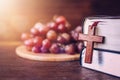 Close-up of wooden cross hang on holy bile over grape on wood plate