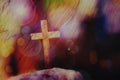 Close up of wooden cross on the rock over blurred colorful Bokeh light