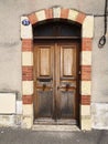 Close-up on a wooden door, worn by time, framed in red and beige bricks