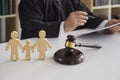 Wooden figurines of family with child and gavel on background of judge conducting divorce process.