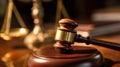 Close up of a wooden gavel on a judge\'s desk with scales of justice in the soft-focused background, law and order