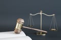 Close up of wooden gavel, scales and book/journal on gray backdrop. Lawyer, justice and punishment concept. Royalty Free Stock Photo