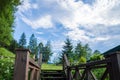 Close up. The wooden handrails of the old pier lead to a beautiful green glade against the blue serene sky. In the forest Royalty Free Stock Photo