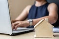 Close up wooden House model, Businesswoman using laptop. housing purchase, Property, real estate and insurance concepts