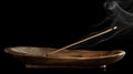 A close up of a wooden incense holder with a stick of fragrant incense burning and emanating smoke. The image invokes a Royalty Free Stock Photo