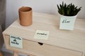 Close-up of wooden nightstand with cup of coffee and green domestic plant