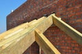 Close up on wooden rafters, eaves, wooden beams installed on brick wall with bitumen waterproofing membrane and metal anchors atta