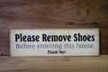 Close up wooden sign please remove shoes sign.