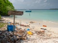 CLOSE UP: Wooden sign prohibits littering on a white sand beach full of garbage