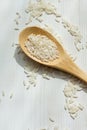 Close-up of wooden spoon with raw white rice, on white wooden table, horizonta