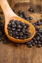 Close-up of wooden spoon with roasted coffee beans on wooden table, Royalty Free Stock Photo