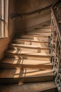 Close-up of wooden staircase on the sunlight and Nouveau style iron balustrade in Paris.
