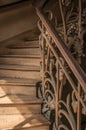 Close-up of wooden staircase on the sunlight and Nouveau style iron balustrade in Paris.