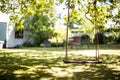 Close up wooden swing under the tree in the garden, close up abstrack soft focus bokeh background on a colorful summer day with su