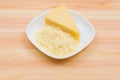 Close-up on a wooden table in a plate is Parmesan cheese in grated and brick form. The concept of solid dairy products Royalty Free Stock Photo