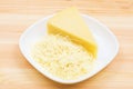 Close-up on a wooden table in a plate is Parmesan cheese in grated and brick form. The concept of solid dairy products Royalty Free Stock Photo