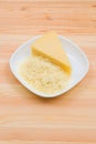 Close-up on a wooden table in a plate is Parmesan cheese in grated and brick form. The concept of solid dairy products Royalty Free Stock Photo